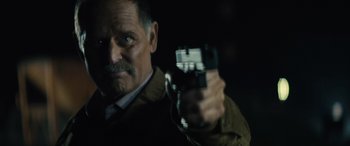 Movie still from “The Locksmith” (2023), directed by Nicolas Harvard – A person holding a gun; Close Up shot, Low angle