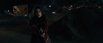 Movie still from “The Locksmith” (2023), directed by Nicolas Harvard – A woman in a red jacket holding a gun in her hand; Medium shot, Over the shoulder angle