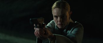Movie still from “The Locksmith” (2023), directed by Nicolas Harvard – A woman is holding a gun in a dark room; Close Up shot, Low angle