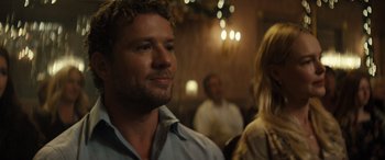 Movie still from “The Locksmith” (2023), directed by Nicolas Harvard – A person in a room with other people; Close Up shot, Over the shoulder angle