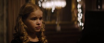 Movie still from “The Locksmith” (2023), directed by Nicolas Harvard – A young girl with long blonde hair looking to her left; Close Up shot, Over the shoulder angle