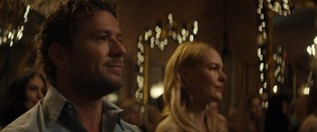 Movie still from “The Locksmith” (2023), directed by Nicolas Harvard – A man and a woman are sitting in front of lights; Close Up shot, Over the shoulder angle