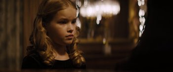 Movie still from “The Locksmith” (2023), directed by Nicolas Harvard – A little girl sitting in front of a chandelier; Close Up shot, Over the shoulder angle