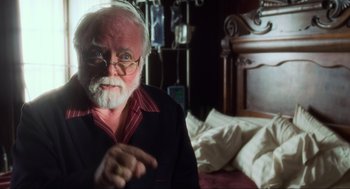 Movie still from “The Lost World: Jurassic Park” (1997), directed by Steven Spielberg – An old man with a beard and glasses is sitting in a bed; Close Up shot, Over the shoulder angle