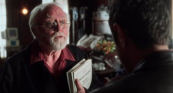 Movie still from “The Lost World: Jurassic Park” (1997), directed by Steven Spielberg – An older man holding a book in front of a younger man; Close Up shot, Over the shoulder angle