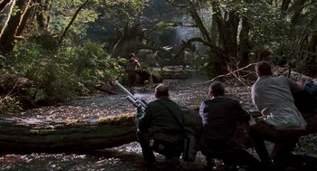 Movie still from “The Lost World: Jurassic Park” (1997), directed by Steven Spielberg – Two men sitting on a fallen tree in the woods; Wide shot, Over the shoulder angle
