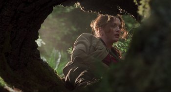 Movie still from “The Lost World: Jurassic Park” (1997), directed by Steven Spielberg – A woman is standing in a tree looking at the camera; Medium shot, Low angle