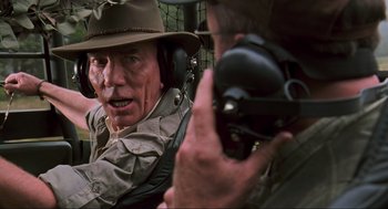 Movie still from “The Lost World: Jurassic Park” (1997), directed by Steven Spielberg – An older man wearing a hat and ear muffs talking to an older man wearing headphones; Close Up shot, Over the shoulder angle