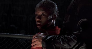 Movie still from “The Lost World: Jurassic Park” (1997), directed by Steven Spielberg – A person holding a person's hand in front of a chain link fence at night; Close Up shot, Low angle