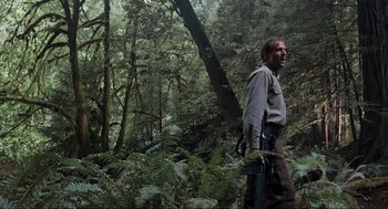 Movie still from “The Lost World: Jurassic Park” (1997), directed by Steven Spielberg – A man standing in the middle of a lush green forest; Medium shot, Low angle