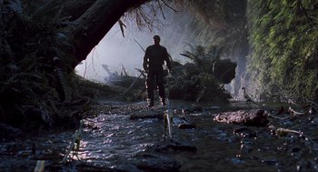 Movie still from “The Lost World: Jurassic Park” (1997), directed by Steven Spielberg – A man standing in the middle of a river; Wide shot, Low angle