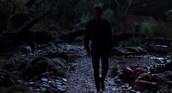 Movie still from “The Lost World: Jurassic Park” (1997), directed by Steven Spielberg – A man is walking in the dark in the woods; Wide shot, Low angle