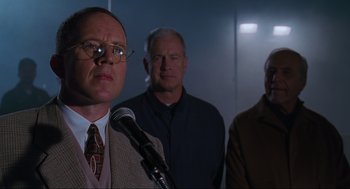 Movie still from “The Lost World: Jurassic Park” (1997), directed by Steven Spielberg – A man with a microphone in front of two other men; Close Up shot, Low angle