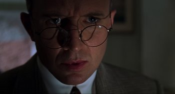 Movie still from “The Lost World: Jurassic Park” (1997), directed by Steven Spielberg – A person wearing a suit and glasses; Close Up shot, Low angle