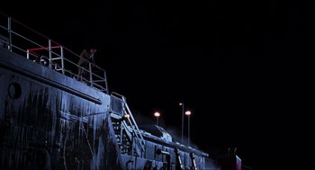 Movie still from “The Lost World: Jurassic Park” (1997), directed by Steven Spielberg – A man standing on top of a metal structure at night; Extreme Wide shot, Low angle
