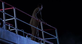 Movie still from “The Lost World: Jurassic Park” (1997), directed by Steven Spielberg – A man in a suit climbing a railing at night; Wide shot, Low angle