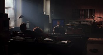Movie still from “The Lost World: Jurassic Park” (1997), directed by Steven Spielberg – A man is sitting in front of a television in a dark room; Wide shot, Over the shoulder angle