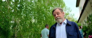 Movie still from “The Machine” (2023), directed by Peter Atencio – An older man standing in front of some trees; Medium shot, Low angle