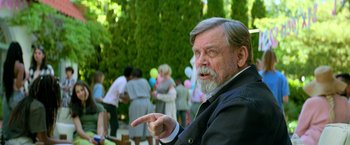 Movie still from “The Machine” (2023), directed by Peter Atencio – An older man with a gray beard is pointing to the side; Medium shot, Over the shoulder angle
