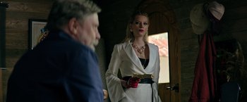 Movie still from “The Machine” (2023), directed by Peter Atencio – A woman in a white jacket is holding a gun; Medium shot, Over the shoulder angle