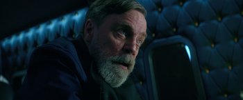 Movie still from “The Machine” (2023), directed by Peter Atencio – An older man with a beard and a mustache; Close Up shot, Low angle