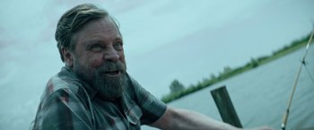 Movie still from “The Machine” (2023), directed by Peter Atencio – An old man with a beard is smiling for the camera; Close Up shot, Over the shoulder angle