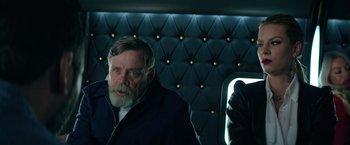 Movie still from “The Machine” (2023), directed by Peter Atencio – An older man with a beard and a jacket; Close Up shot, Over the shoulder angle