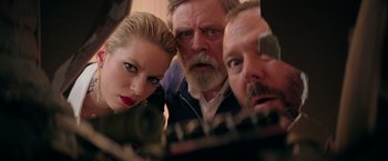 Movie still from “The Machine” (2023), directed by Peter Atencio – A man and two women looking at the camera; Close Up shot, Low angle
