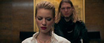 Movie still from “The Machine” (2023), directed by Peter Atencio – A woman with tattoos on her face and a man with tattoos on her neck; Close Up shot, Low angle