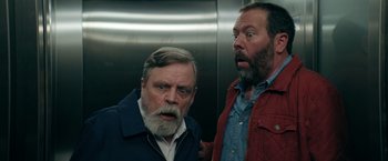 Movie still from “The Machine” (2023), directed by Peter Atencio – Two men standing next to each other in an elevator; Close Up shot, Low angle