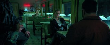 Movie still from “The Machine” (2023), directed by Peter Atencio – A woman sitting at a table in a restaurant; Medium shot, Over the shoulder angle