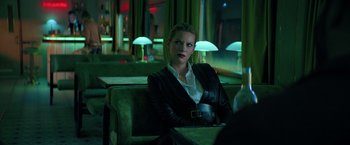 Movie still from “The Machine” (2023), directed by Peter Atencio – A woman in a leather jacket sitting in a chair; Medium shot, Over the shoulder angle