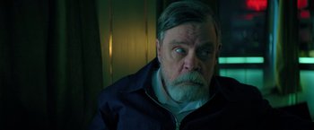 Movie still from “The Machine” (2023), directed by Peter Atencio – An older man with a beard and a mustache; Close Up shot, Over the shoulder angle