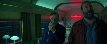 Movie still from “The Machine” (2023), directed by Peter Atencio – An older man holding a cell phone up to his ear; Medium shot, Low angle