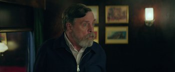 Movie still from “The Machine” (2023), directed by Peter Atencio – An older man with a beard and mustache looking to his left; Close Up shot, Over the shoulder angle