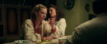 Movie still from “The Machine” (2023), directed by Peter Atencio – Two women sitting at a table with a bowl of fruit; Medium shot, Over the shoulder angle