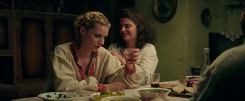 Movie still from “The Machine” (2023), directed by Peter Atencio – Two women sitting at a table with a plate of food; Medium shot, Over the shoulder angle