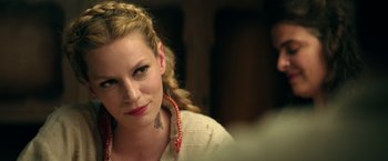 Movie still from “The Machine” (2023), directed by Peter Atencio – A beautiful woman with blonde hair wearing a necklace; Close Up shot, Over the shoulder angle