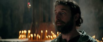 Movie still from “The Machine” (2023), directed by Peter Atencio – A man with a long beard is looking at the camera; Close Up shot, Over the shoulder angle