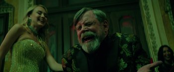 Movie still from “The Machine” (2023), directed by Peter Atencio – An old man with a beard and a green jacket is crying; Close Up shot, Over the shoulder angle