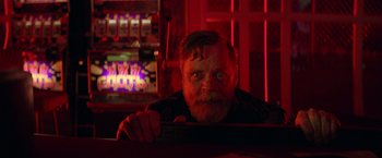 Movie still from “The Machine” (2023), directed by Peter Atencio – A man with a goatee and a beard sitting at a bar; Close Up shot, Low angle