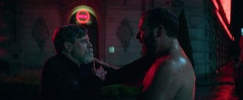 Movie still from “The Machine” (2023), directed by Peter Atencio – Two men are fighting in a dark room; Medium shot, Over the shoulder angle