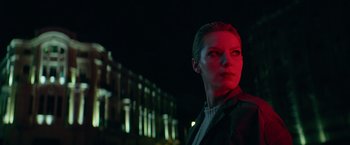 Movie still from “The Machine” (2023), directed by Peter Atencio – A woman in a black jacket standing in front of a building at night; Close Up shot, Low angle
