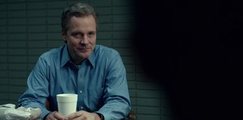 Movie still from “Dopesick” (2021), directed by Danny Strong – A man sitting in a chair holding a coffee cup; Close Up shot, Over the shoulder angle