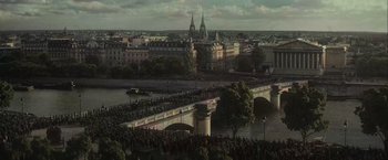 Movie still from “The Mad Women's Ball” (2021), directed by Mélanie Laurent – An aerial view of a crowd of people crossing a bridge; Extreme Wide shot, High angle
