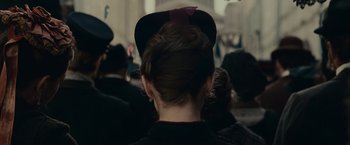 Movie still from “The Mad Women's Ball” (2021), directed by Mélanie Laurent – A woman wearing a hat with a red ribbon on it; Extreme Close Up shot, Over the shoulder angle