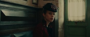 Movie still from “The Mad Women's Ball” (2021), directed by Mélanie Laurent – A woman wearing a red jacket and a black hat; Close Up shot, Low angle