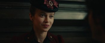 Movie still from “The Mad Women's Ball” (2021), directed by Mélanie Laurent – A woman wearing a hat with a flower on it; Close Up shot, Over the shoulder angle