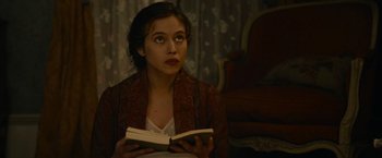 Movie still from “The Mad Women's Ball” (2021), directed by Mélanie Laurent – A woman sitting in front of an open book; Close Up shot, High angle
