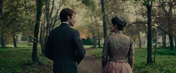Movie still from “The Mad Women's Ball” (2021), directed by Mélanie Laurent – A man and a woman standing next to each other in the woods; Medium shot, Over the shoulder angle